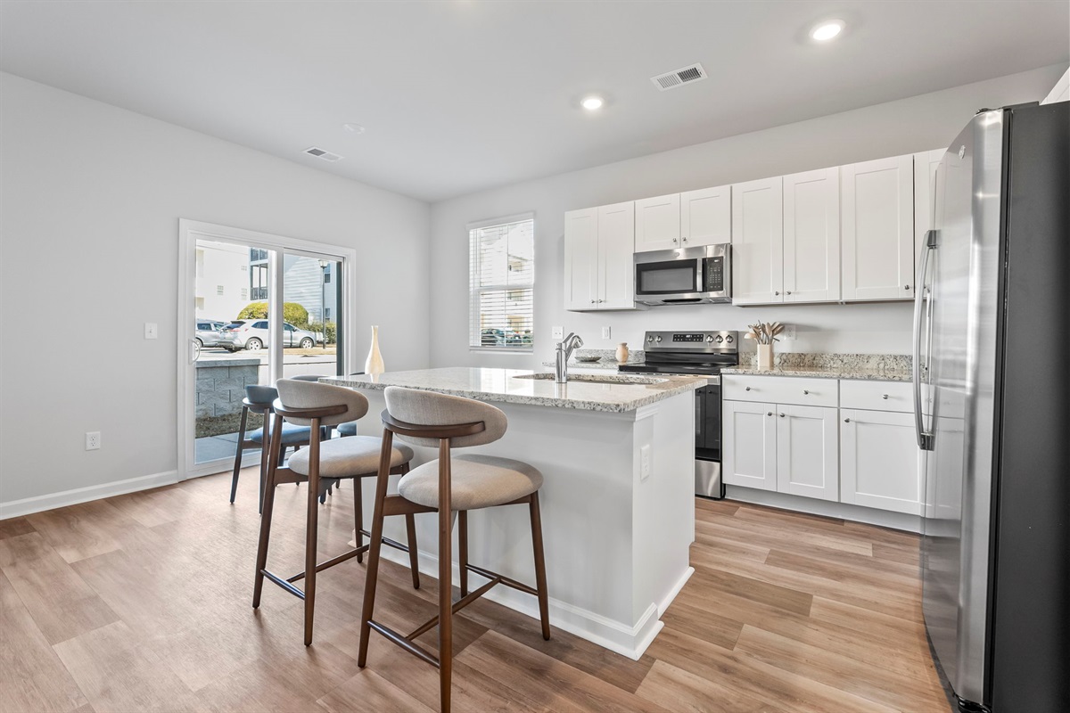 Modern kitchen with granite countertops and stainless steel appliances, dining room table seats 6