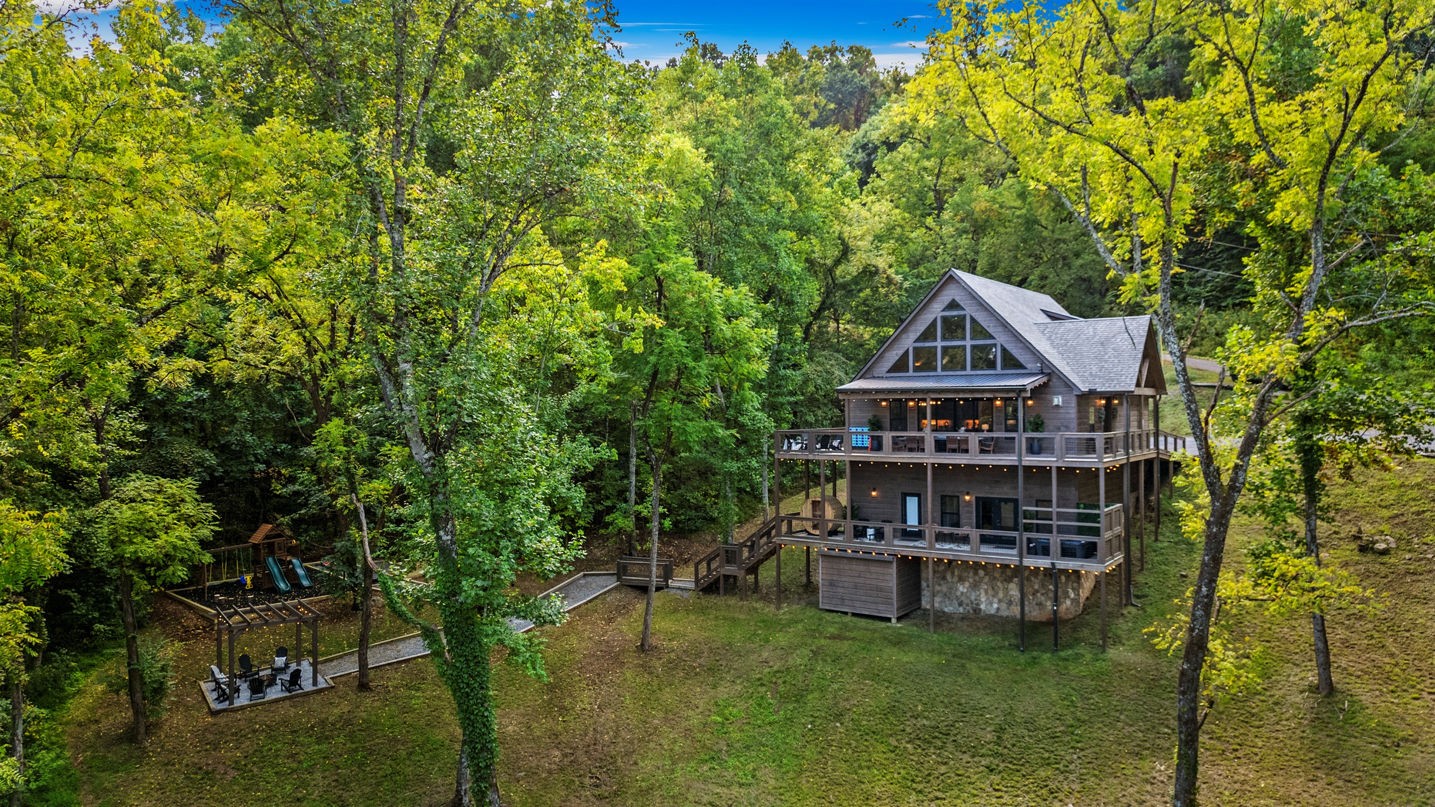 🏡 Big porch energy + playground joy. Whether you're sipping coffee or pushing kiddos on the swings, this is what cabin dreams are made of.