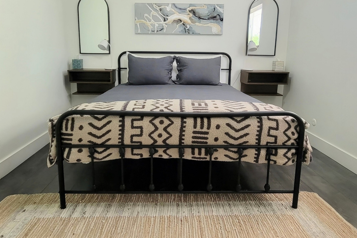 Spacious main bedroom with queen bed, nightstands, and phone charging lights with connecting bathroom.