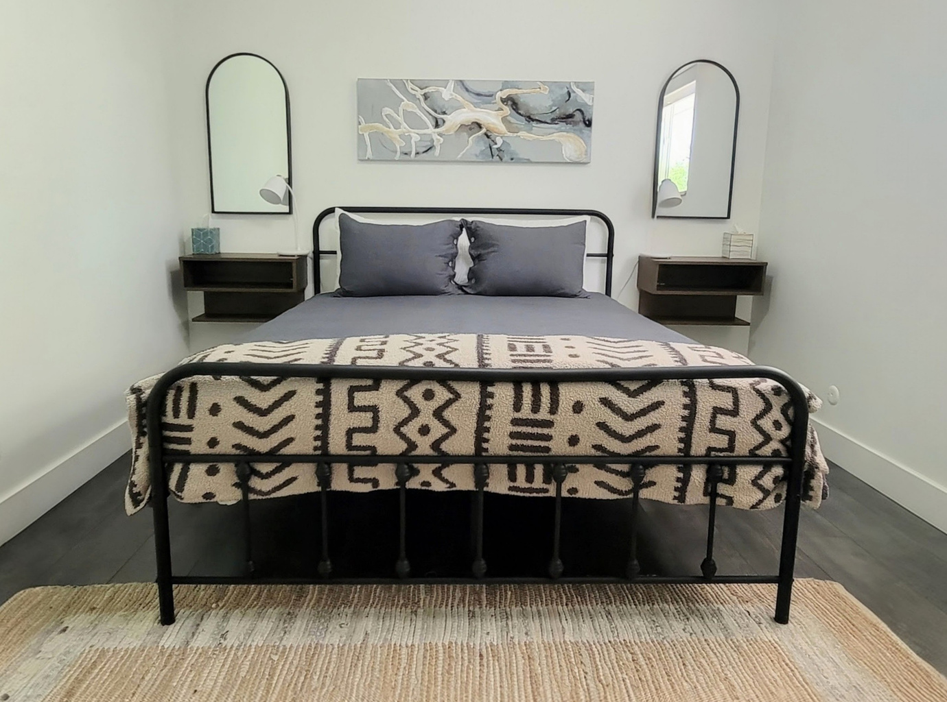 Spacious main bedroom with queen bed, nightstands, and phone charging lights with connecting bathroom.