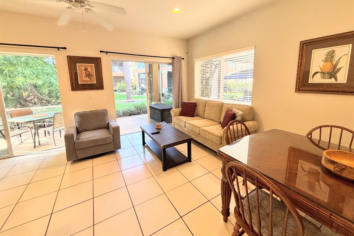Spacious living and dining area with cozy seating, natural light, and sliding glass doors leading to the screened patio.