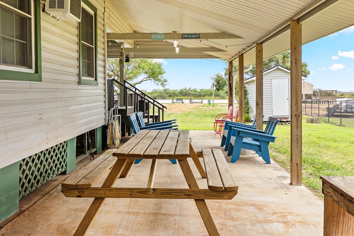 Picnic table under carport with view of large backyard and creek