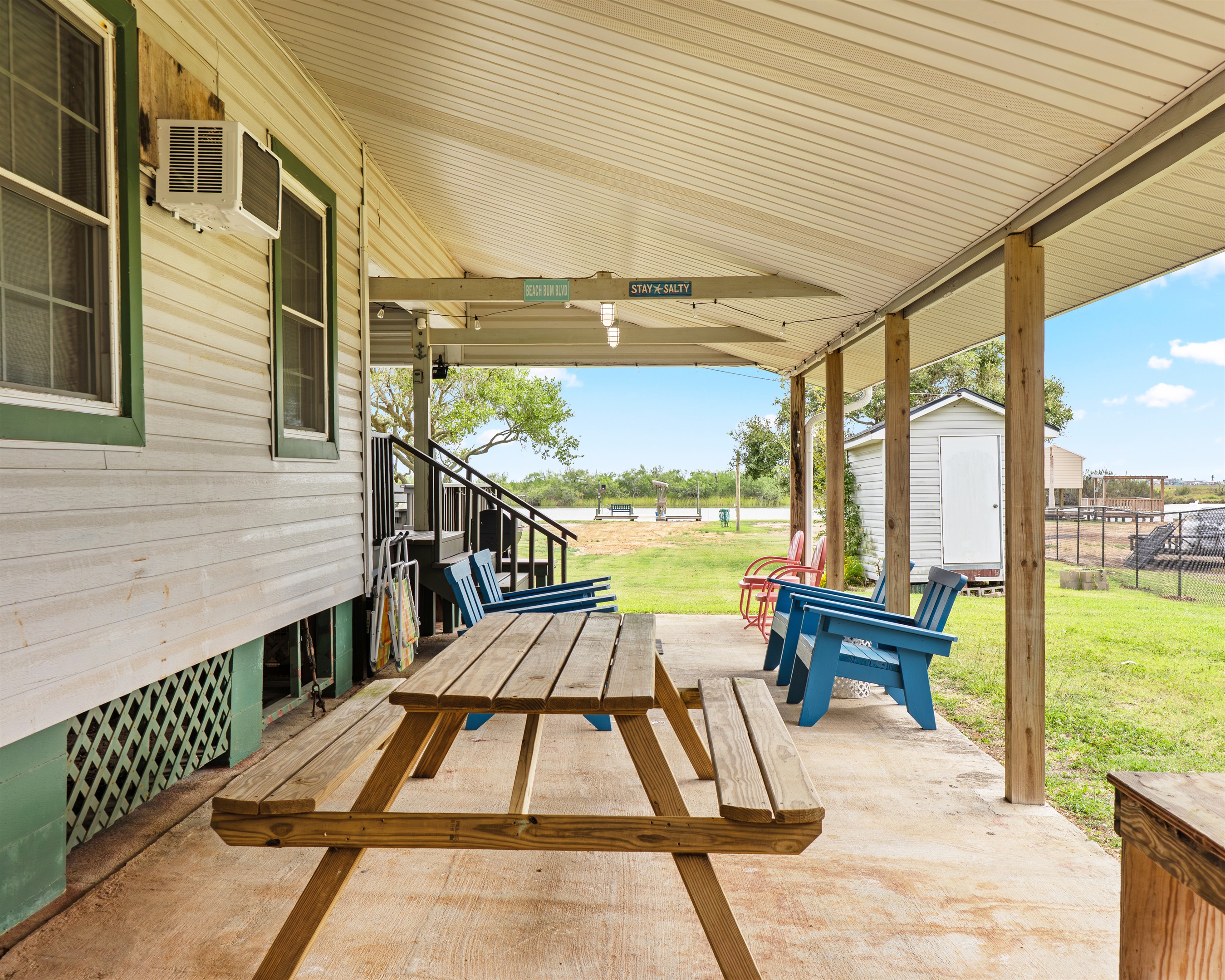 Picnic table under carport with view of large backyard and creek