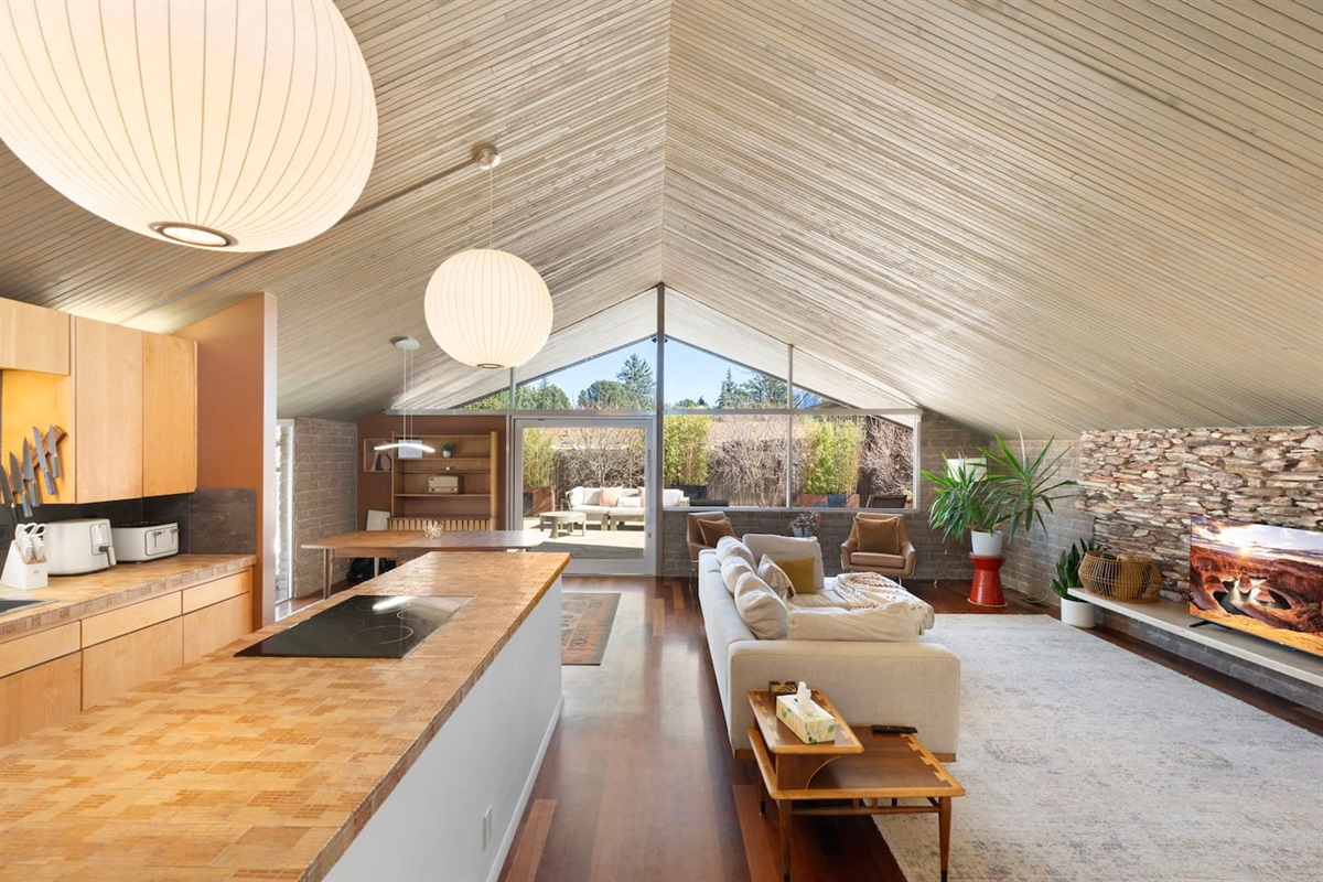 Beautifully designed open living space with soaring vaulted ceilings, expansive windows, and a seamless connection between the kitchen, lounge, and outdoor area.