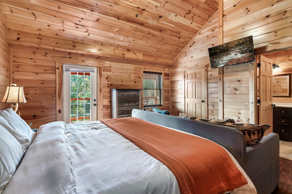 Stretch out in a spacious cabin suite where rustic charm, soft light, and balcony access elevate your stay.