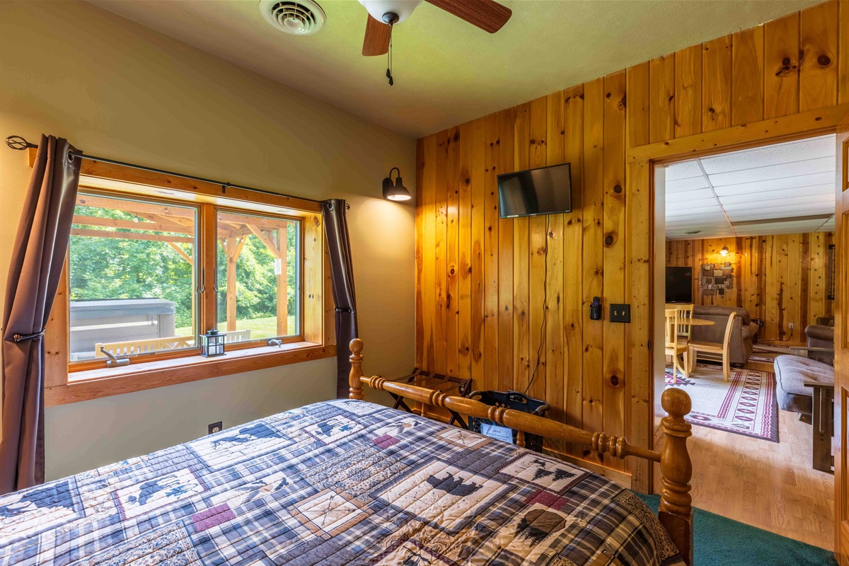 The lower-level bedroom is just outside the game room area and has a wall hanging smart tv.