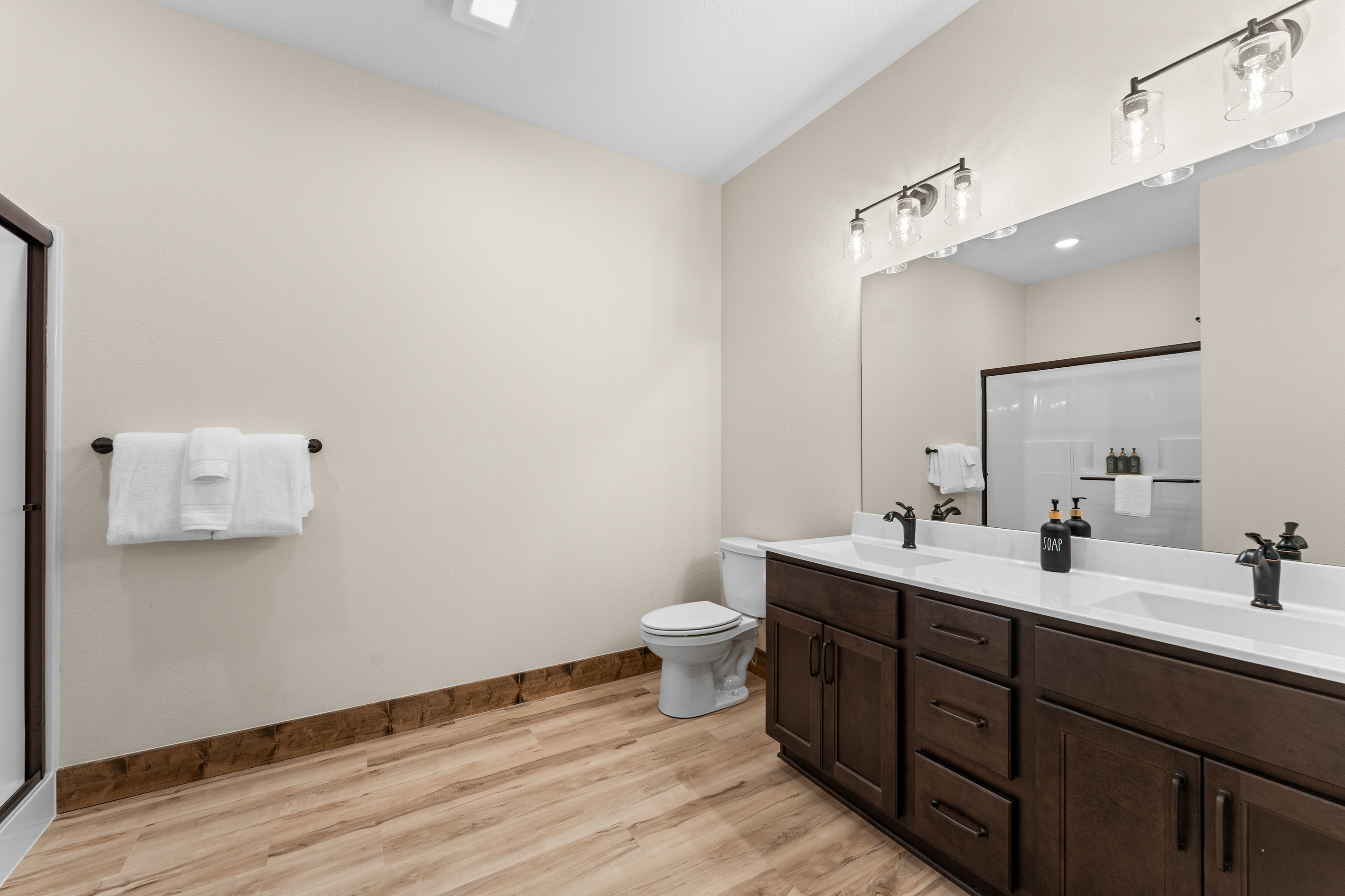 This downstairs queen suite has a roomy bath with double vanity, walk-in shower, and towels stacked and ready.