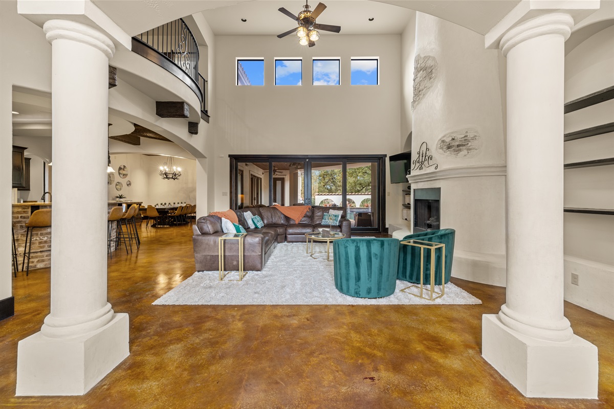 "Welcome to the heart of the house! This spacious living room boasts over 20-foot ceilings, abundant seating, a cozy fireplace, and a smart TV—all with stunning views of the resort-style pool.