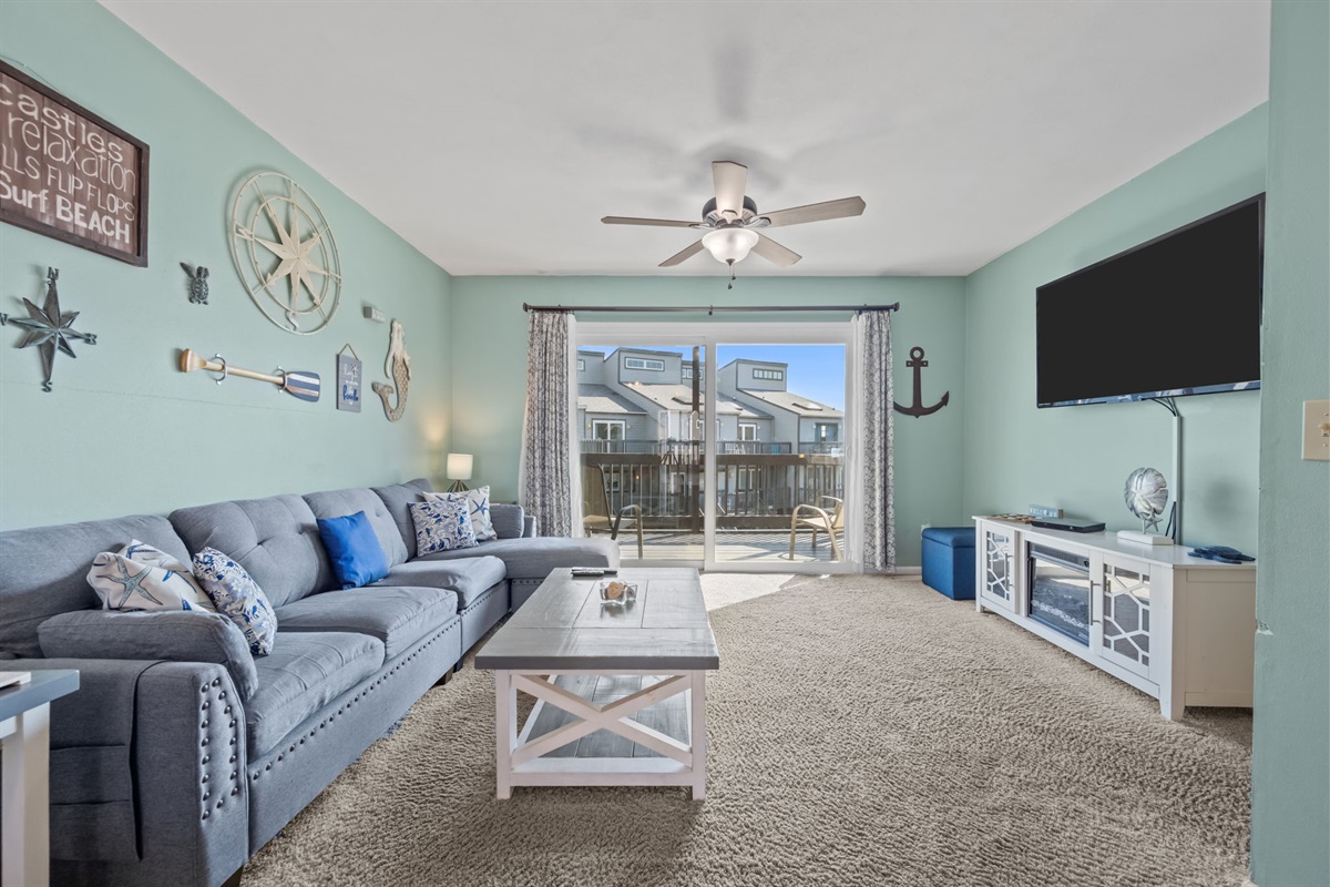 A spacious coastal living area designed for gathering, with comfy seating and easy access to the balcony just steps away