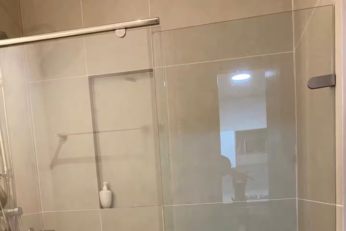Baño con ducha con mampara de vidrio, tocador amplio, espejo y espacio de almacenamiento, ofreciendo a los huéspedes un espacio limpio y práctico para sus rutinas diarias.
