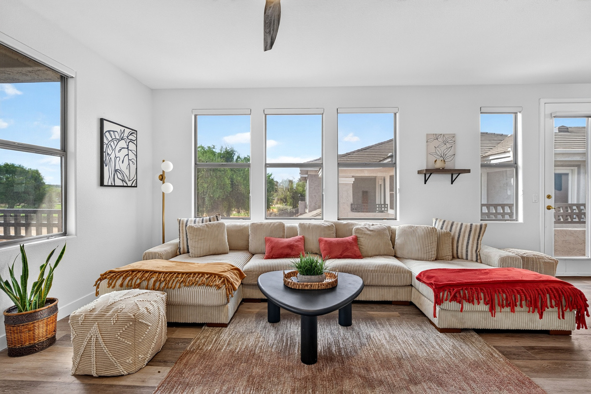 Living room with oversized sectional seating, wide windows, and open views of the desert landscaping outside.