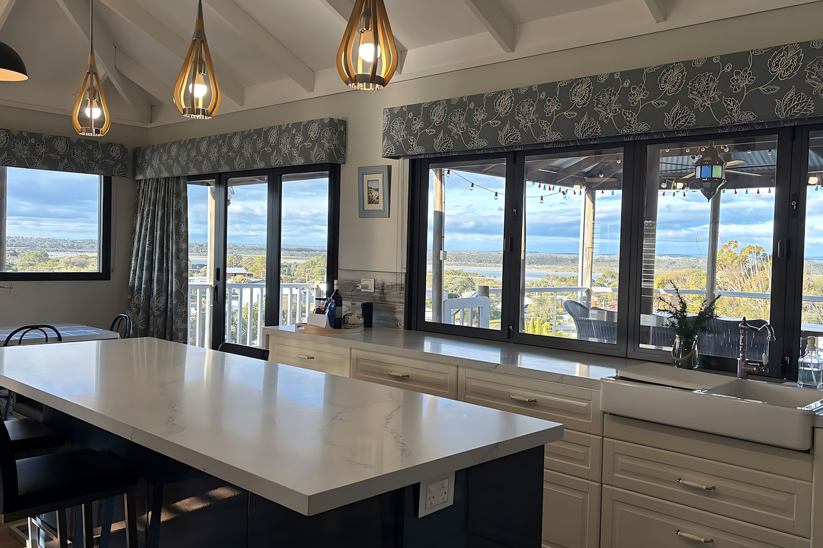 The kitchen opens through wide bifold windows onto the gazebo deck, with a large island bench, a farmhouse sink and views across Preston Beach to Lake Preston and Yalgorup National Park.