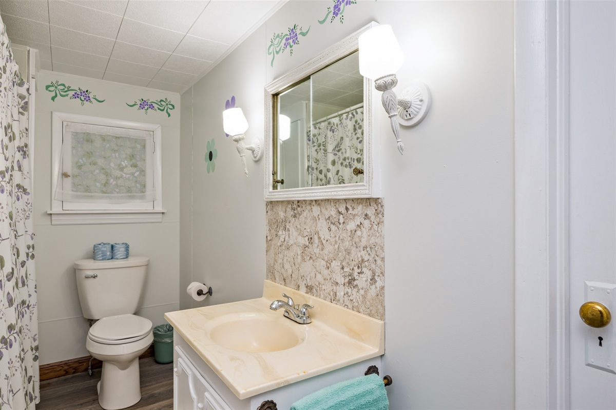 Clean, cheerful full bathroom with floral details and all the essentials for a comfortable stay.