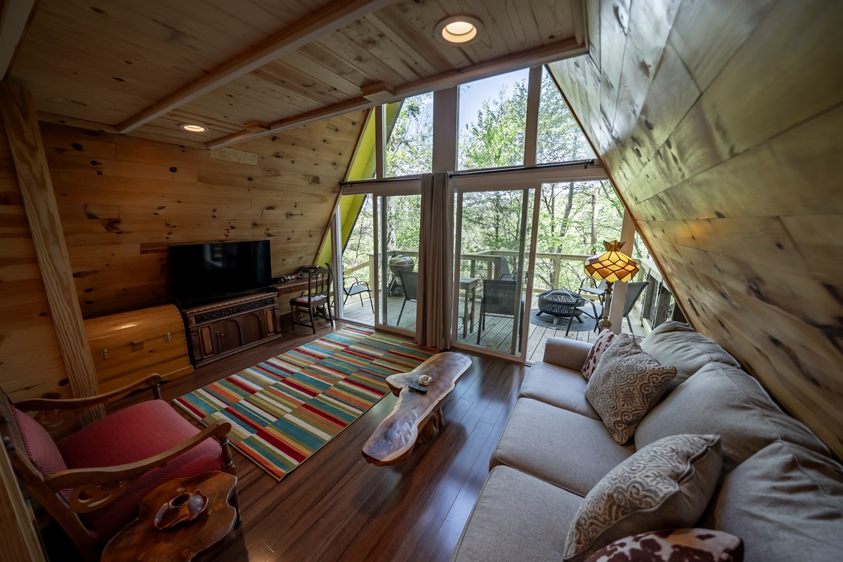 Cozy up in the light-filled living room with floor-to-ceiling windows, a comfortable sofa (that converts to a queen bed), and peaceful wooded views all around.