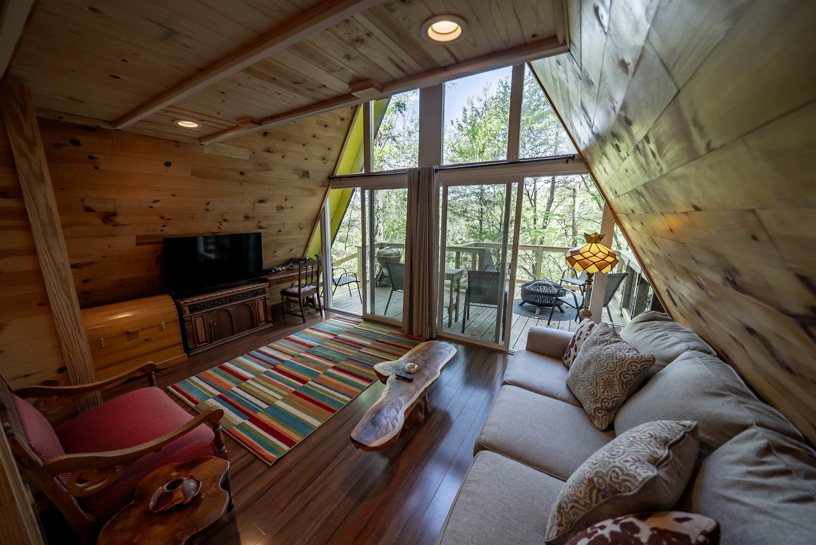 Cozy up in the light-filled living room with floor-to-ceiling windows, a comfortable sofa (that converts to a queen bed), and peaceful wooded views all around.