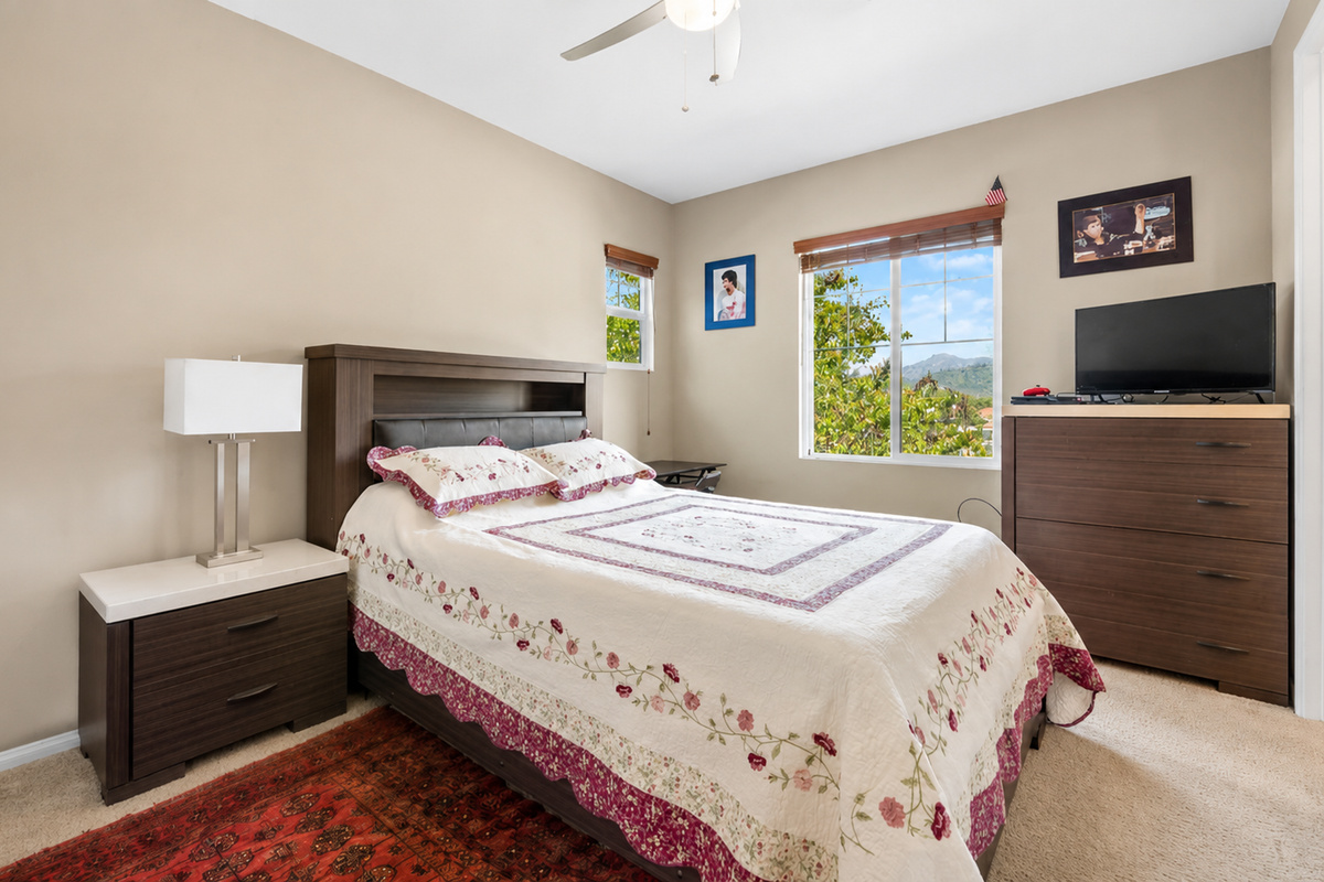 Bedroom with a comfortable bed, dresser storage, TV, and sunny window views.