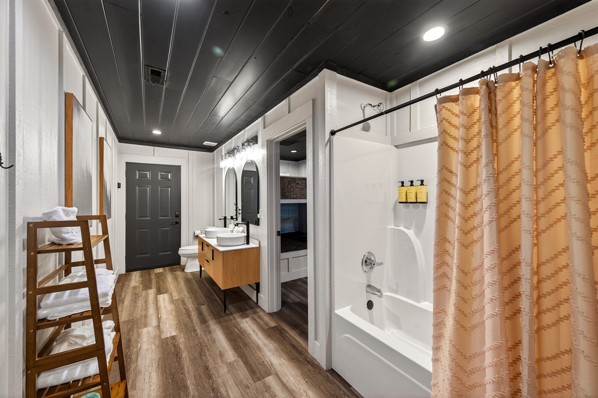 Bunk room bathroom. Double sink vanity, bathtub and shower.