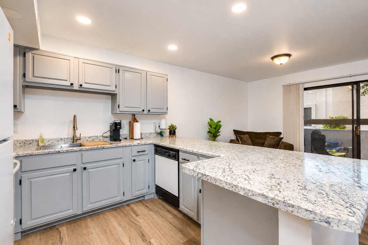 Kitchen with gray cabinets, full appliances, and a wide counter for meals or serving.
