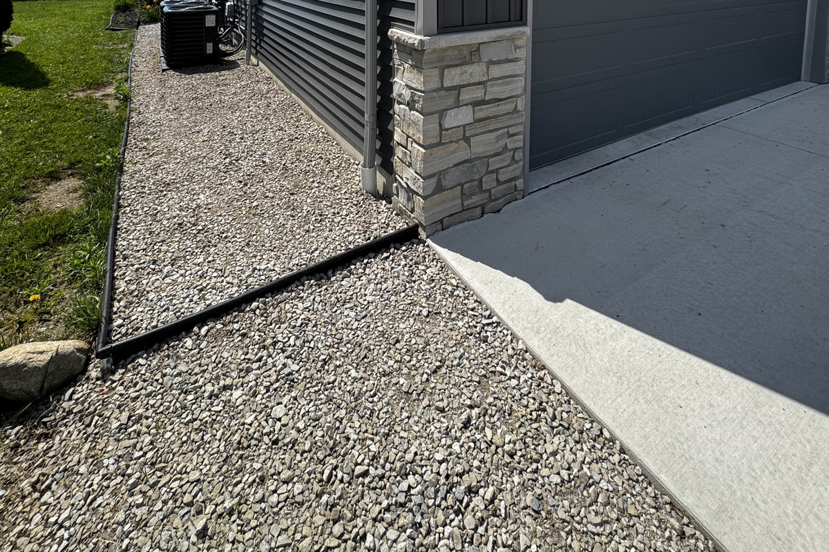 Clean side walkway with gravel and stepping edge along the exterior of the home, connecting the driveway and backyard spaces.