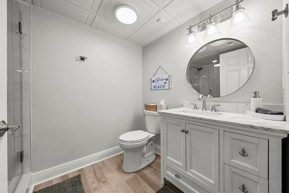 Fresh, coastal-inspired bathroom featuring a spacious marble vanity, modern lighting, and a walk-in shower—designed for comfort and relaxation after a perfect beach day.