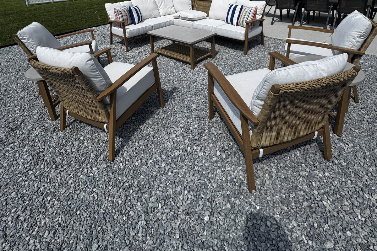 Cozy outdoor lounge seating area with cushioned chairs and coffee table, set on a gravel patio perfect for relaxing and gathering.