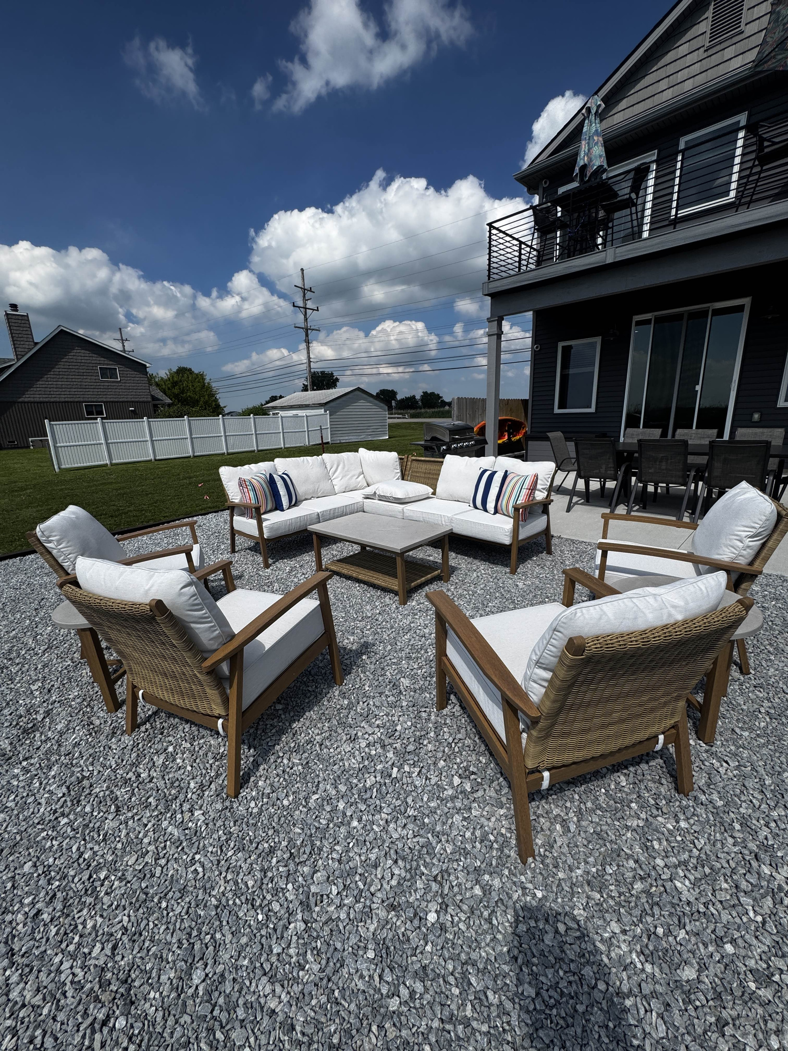 Cozy outdoor lounge seating area with cushioned chairs and coffee table, set on a gravel patio perfect for relaxing and gathering.