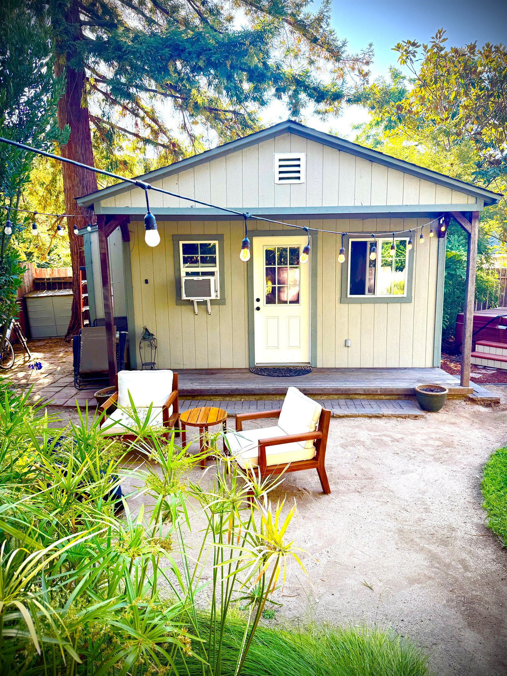 Charming home exterior framed by tall trees & blue skies