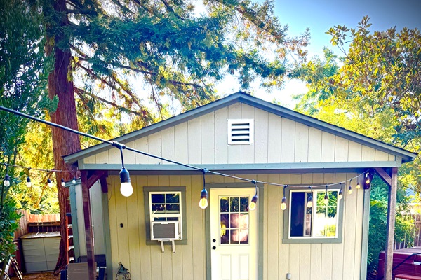 Charming home exterior framed by tall trees & blue skies