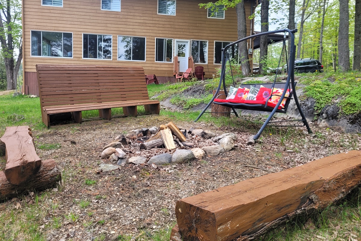 Firepit close to cottage with lots of seating around fire pit and view of lake