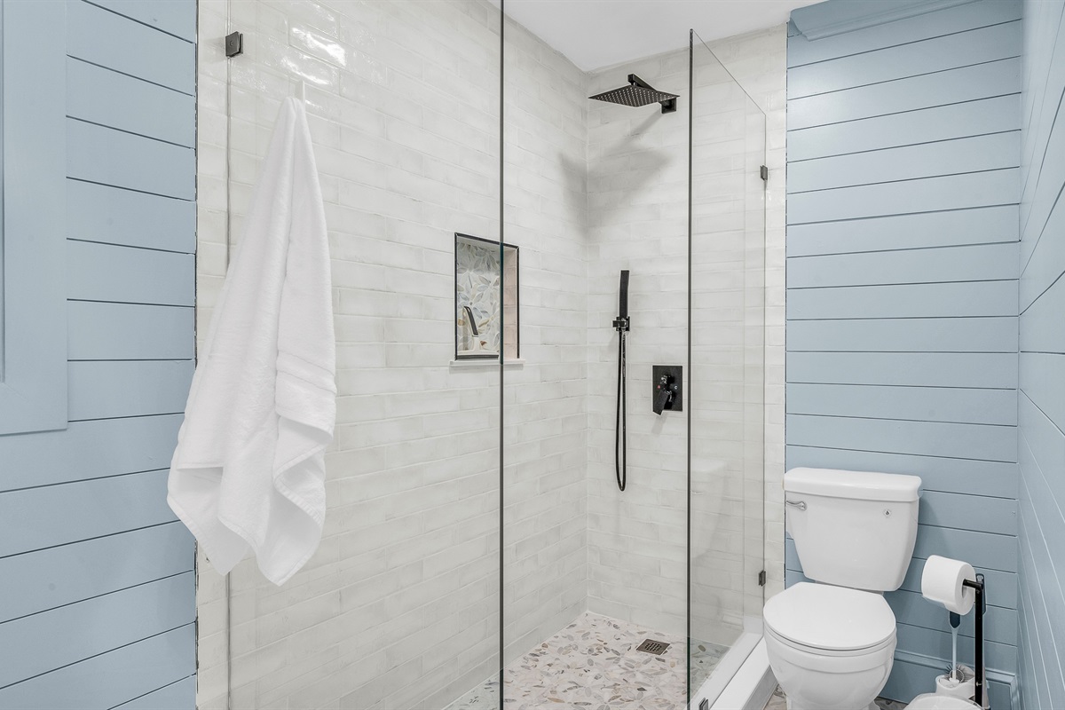 Primary Bathroom: This spa-inspired bathroom features sleek coastal design with a walk-in glass shower, modern fixtures and soft natural light- creating a serene retreat for relaxation and rejuvenation