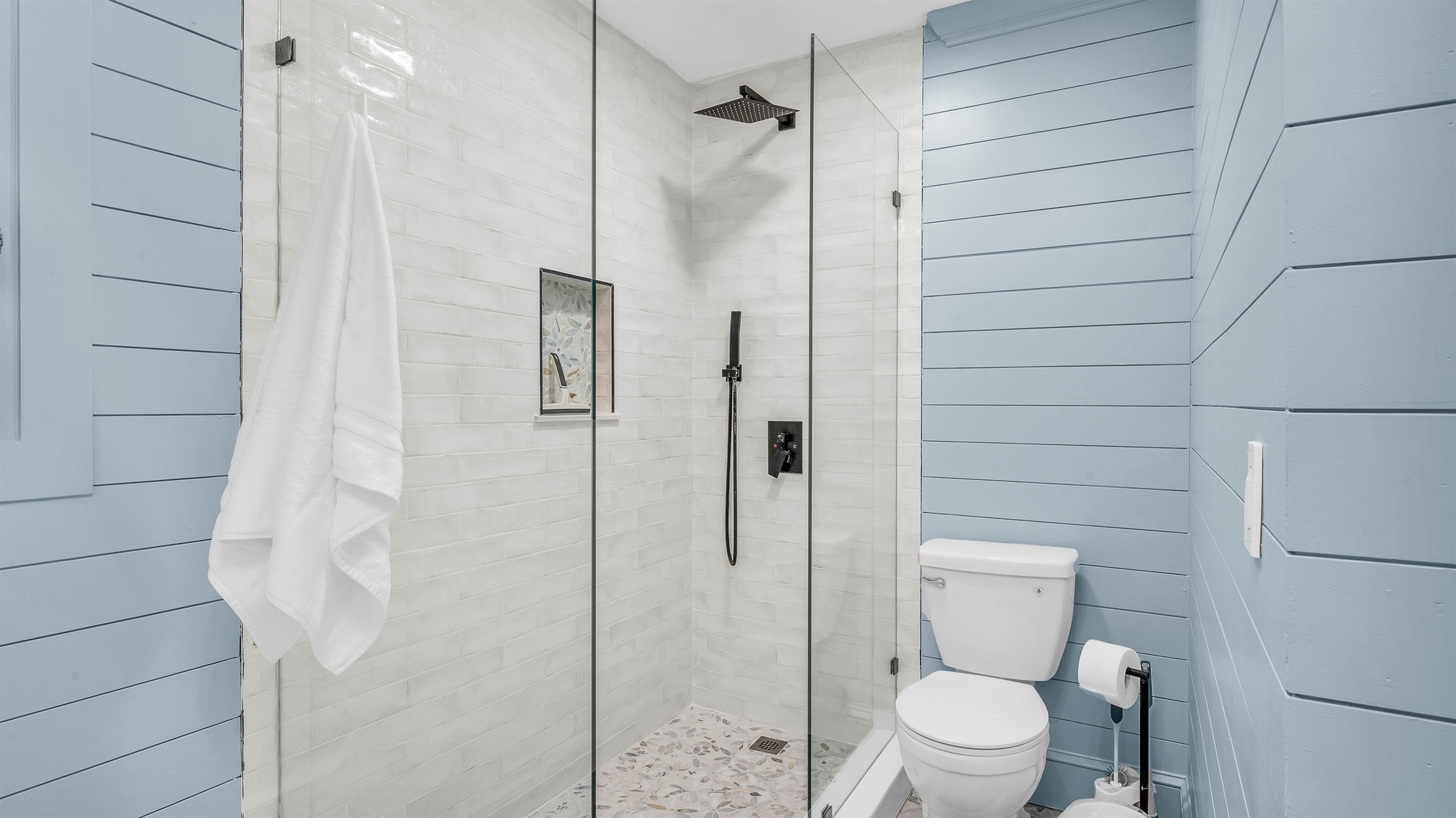 Primary Bathroom: This spa-inspired bathroom features sleek coastal design with a walk-in glass shower, modern fixtures and soft natural light- creating a serene retreat for relaxation and rejuvenation