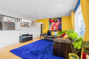 A spacious living room with a soft blue carpet and lush indoor plants, blending comfort with natural beauty for a serene living space.