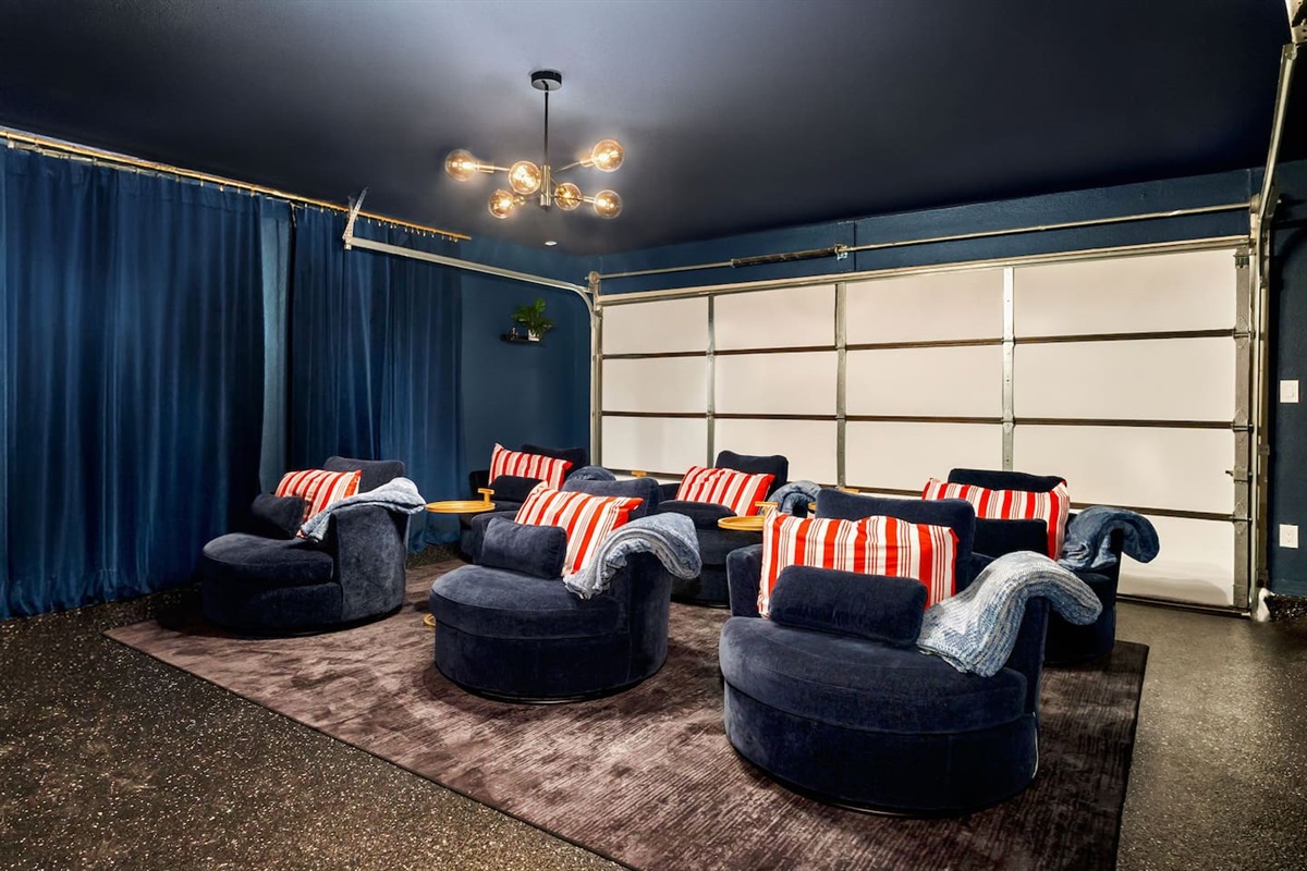Private movie theater room with plush lounge recliners, cozy throw blankets, striped pillows, moody lighting, and blackout curtains—perfect for family movie nights, marathons, and relaxing after a fun-filled San Antonio day. 
