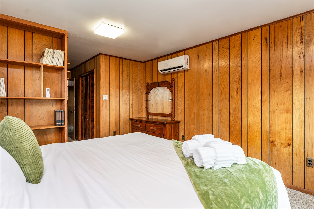 Charming bedroom complete with rustic paneling, built-in shelving, and a vintage dresser, blending comfort with character.