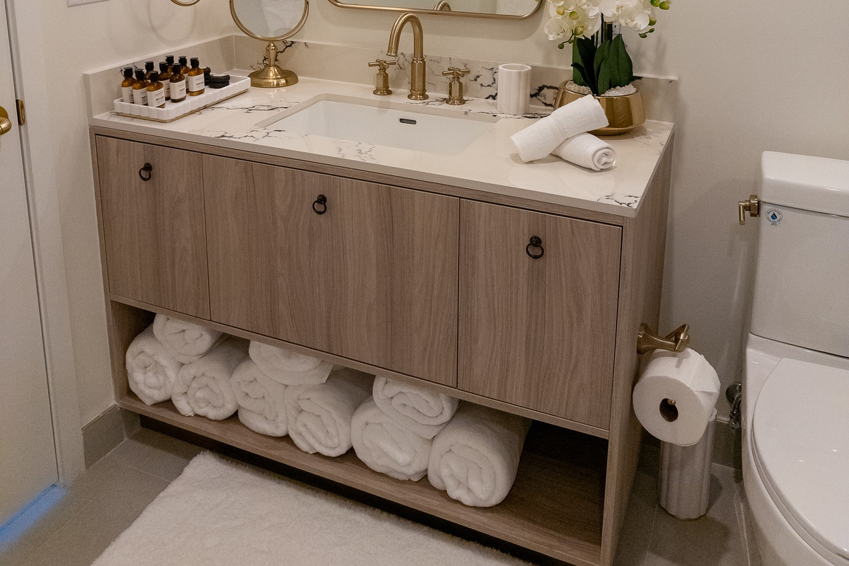 A hotel-style vanity with a wide mirror, brushed-gold faucet and rolled towels stocked and ready for you.