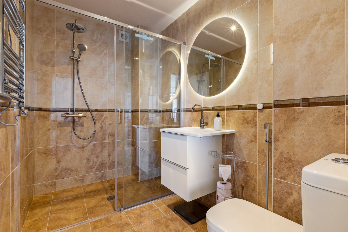 Bathroom with walk-in shower, rainfall showerhead and illuminated mirror.