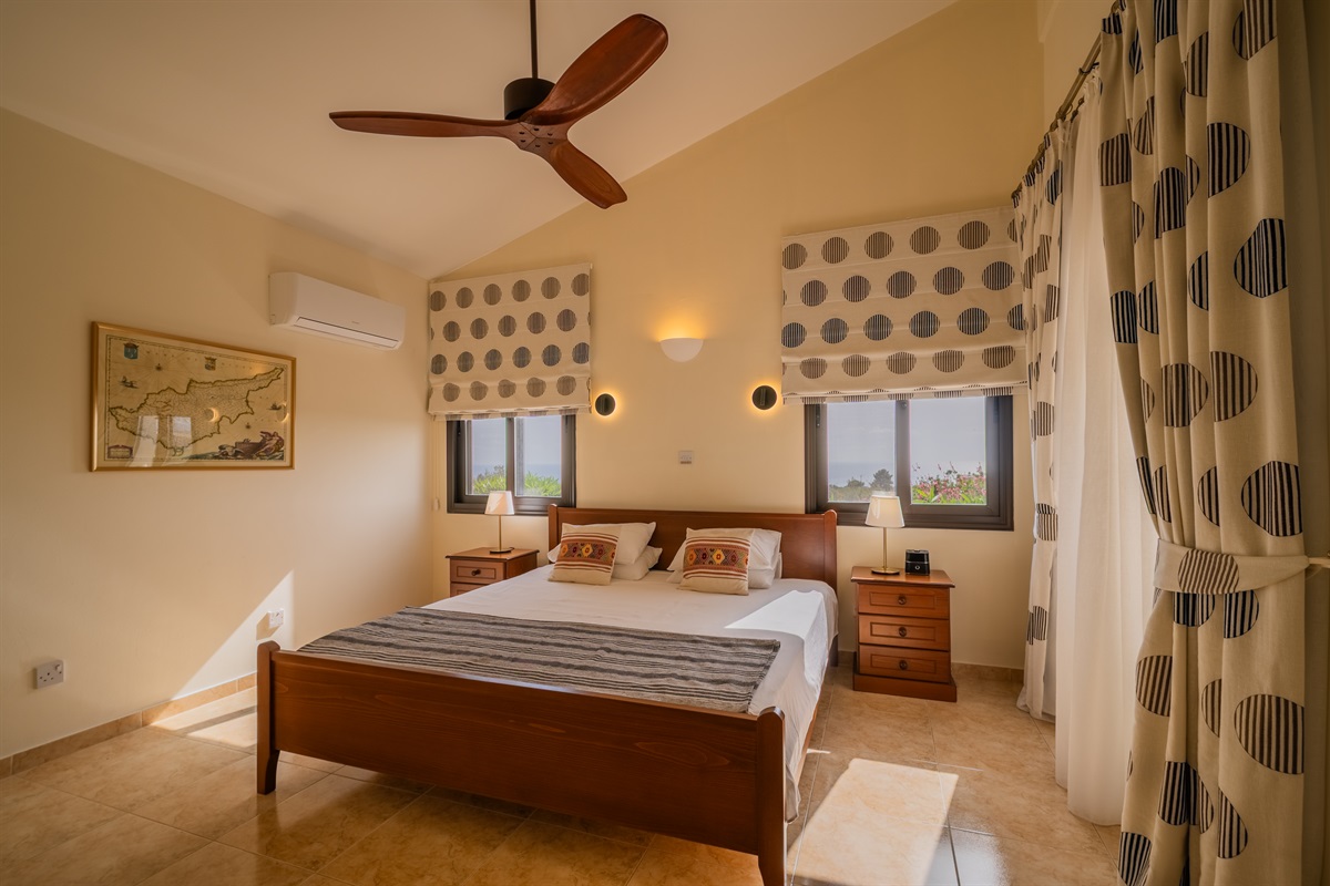 Master king ensuite bedroom with sea views and terrace access. King size bed, ceiling fan, dedicated AC/heating unit, vanity, large built-in wardrobes, bluetooth speaker/alarm clock.