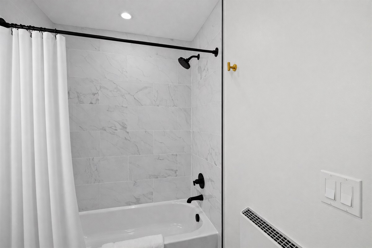 Clean, modern shower with sleek tile, rainfall-style head, and bright lighting—perfect for a refreshing start or a relaxing wind-down.