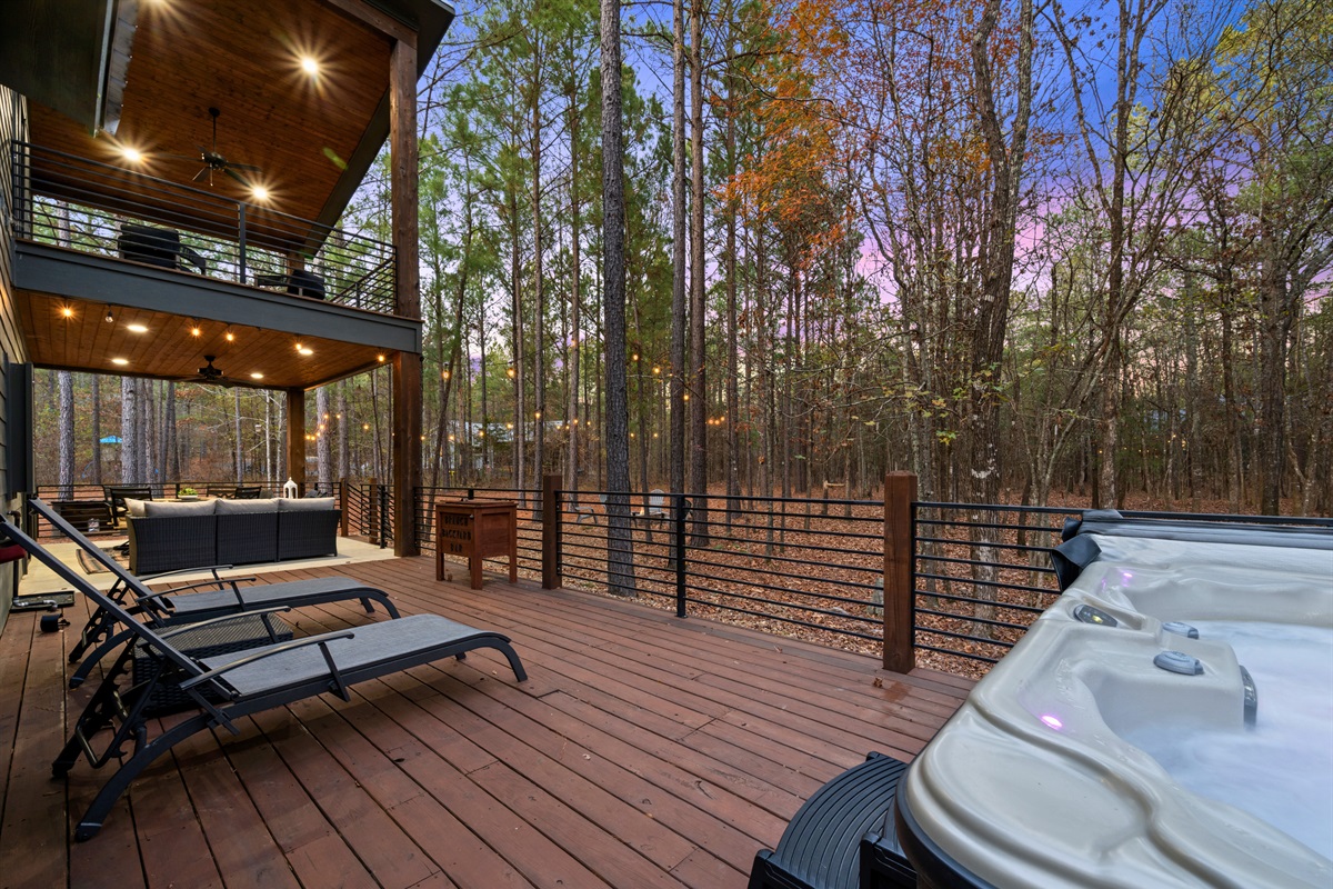 The hot tub deck feels private and serene, surrounded by tall trees and soft ambient lighting.