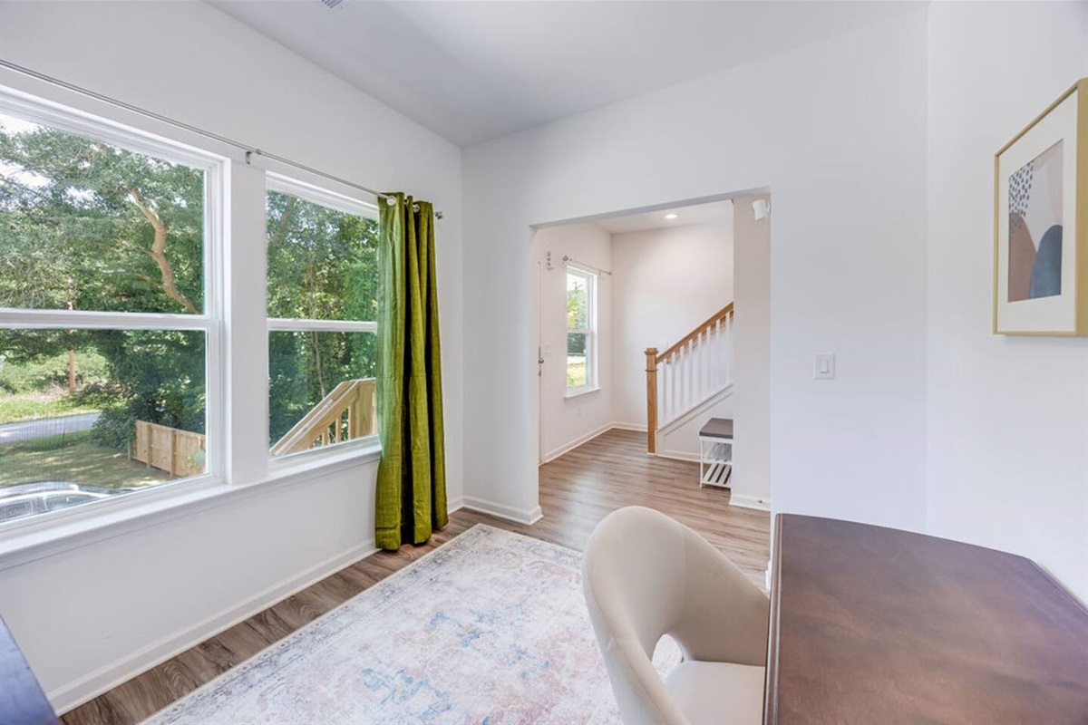 Bright office room with large windows, featuring a Murphy bed that effortlessly folds out into a queen bed, offering versatile space for work or rest.