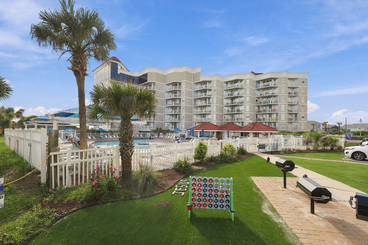 Resort courtyard featuring lush palm trees, green lawn, and fun outdoor lawn games.