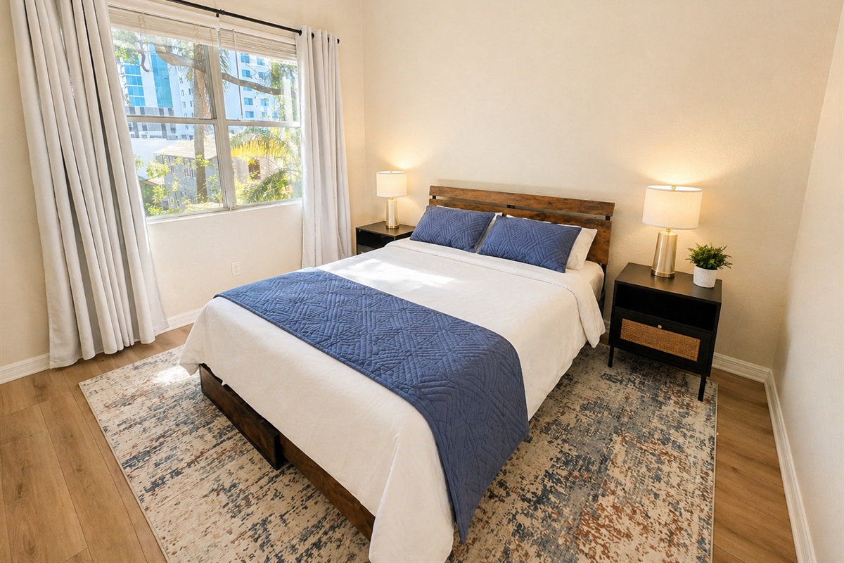 Bright and peaceful bedroom with a comfortable bed, soft linens, and warm wood accents. Large window brings in natural light, while bedside tables and lamps create a cozy, relaxing space for restful nights.