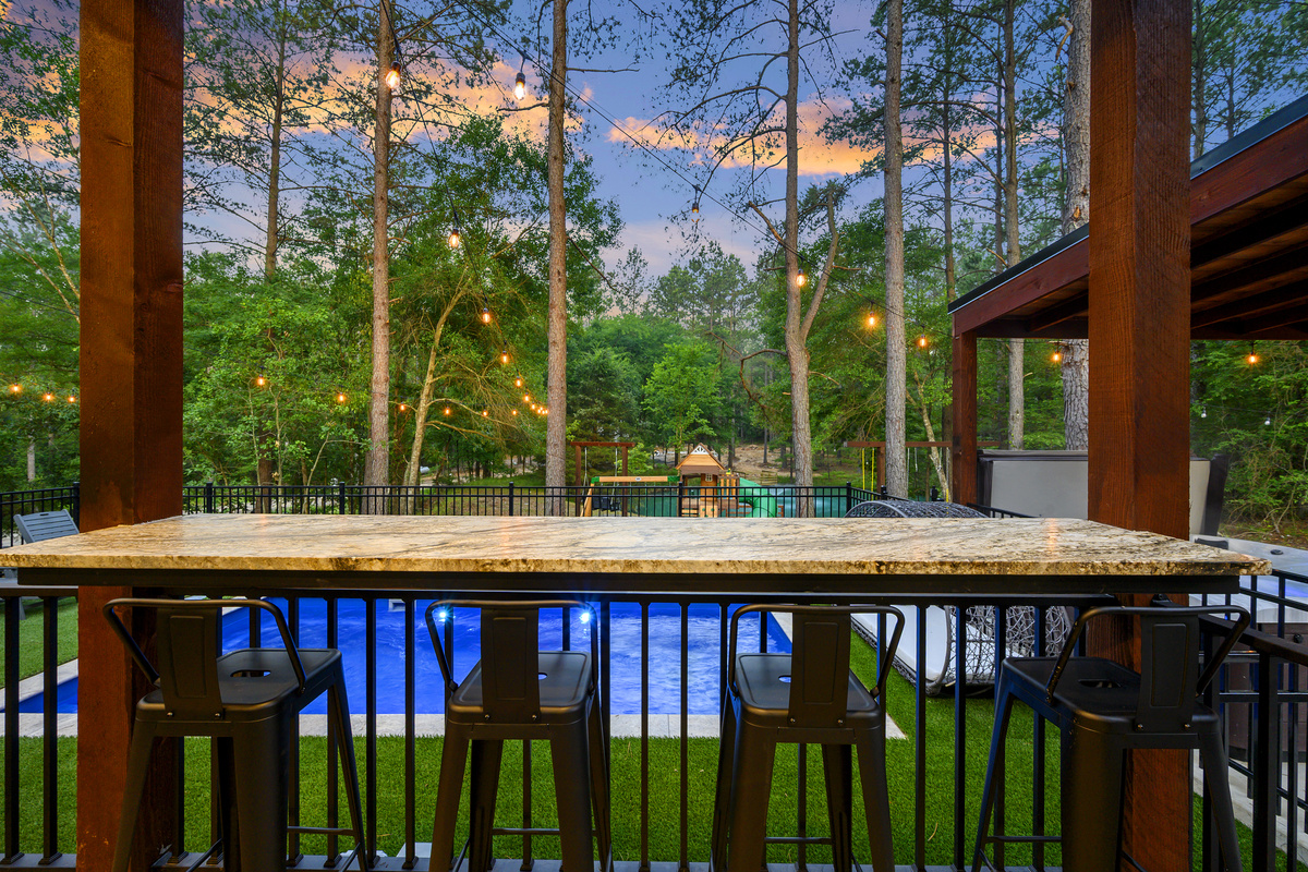 A front-row seat to the fun. The covered bar overlooks the pool, playset, pond & pines, so you can relax while still being part of everything happening outside.