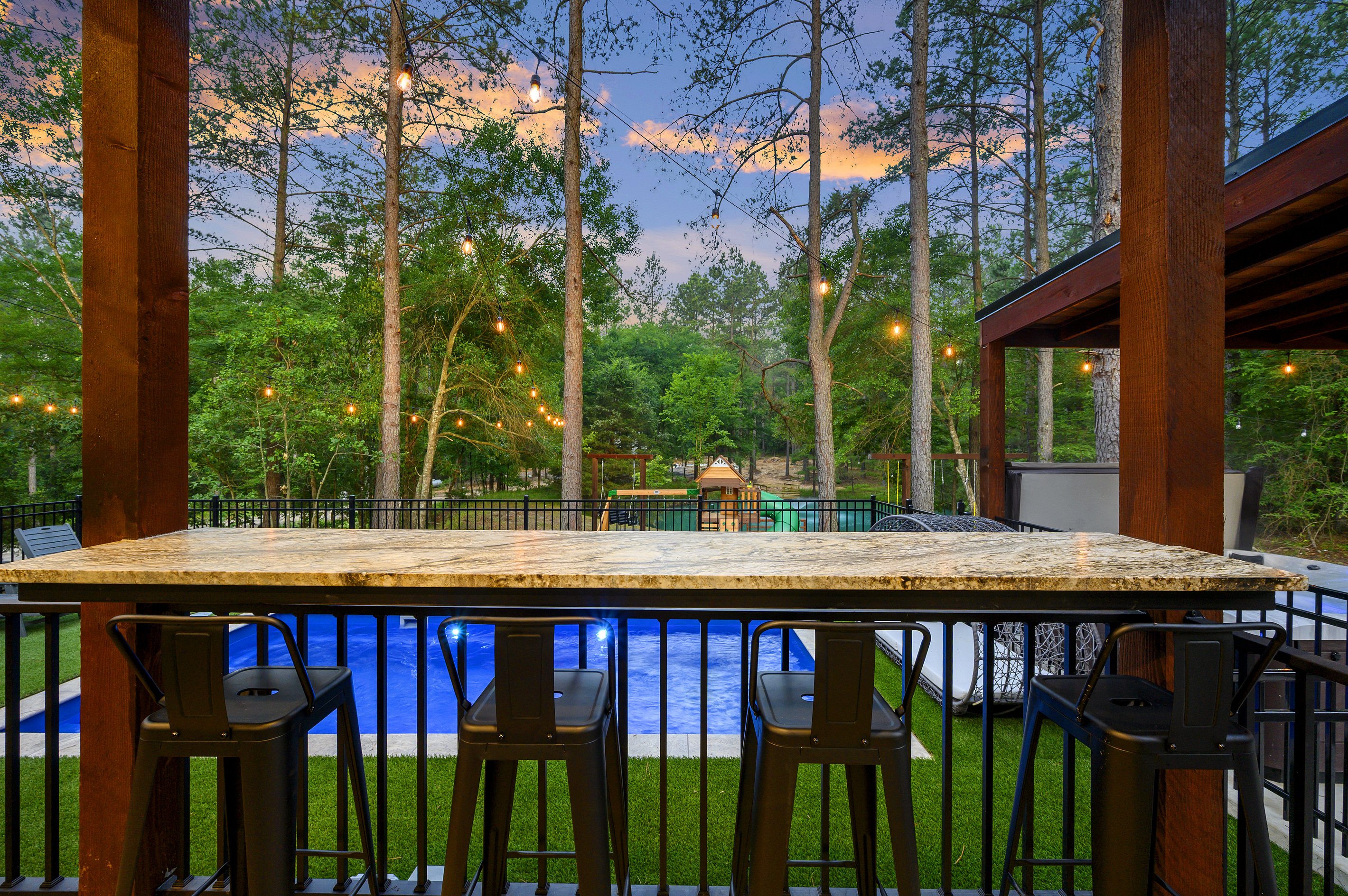 A front-row seat to the fun. The covered bar overlooks the pool, playset, pond & pines, so you can relax while still being part of everything happening outside.