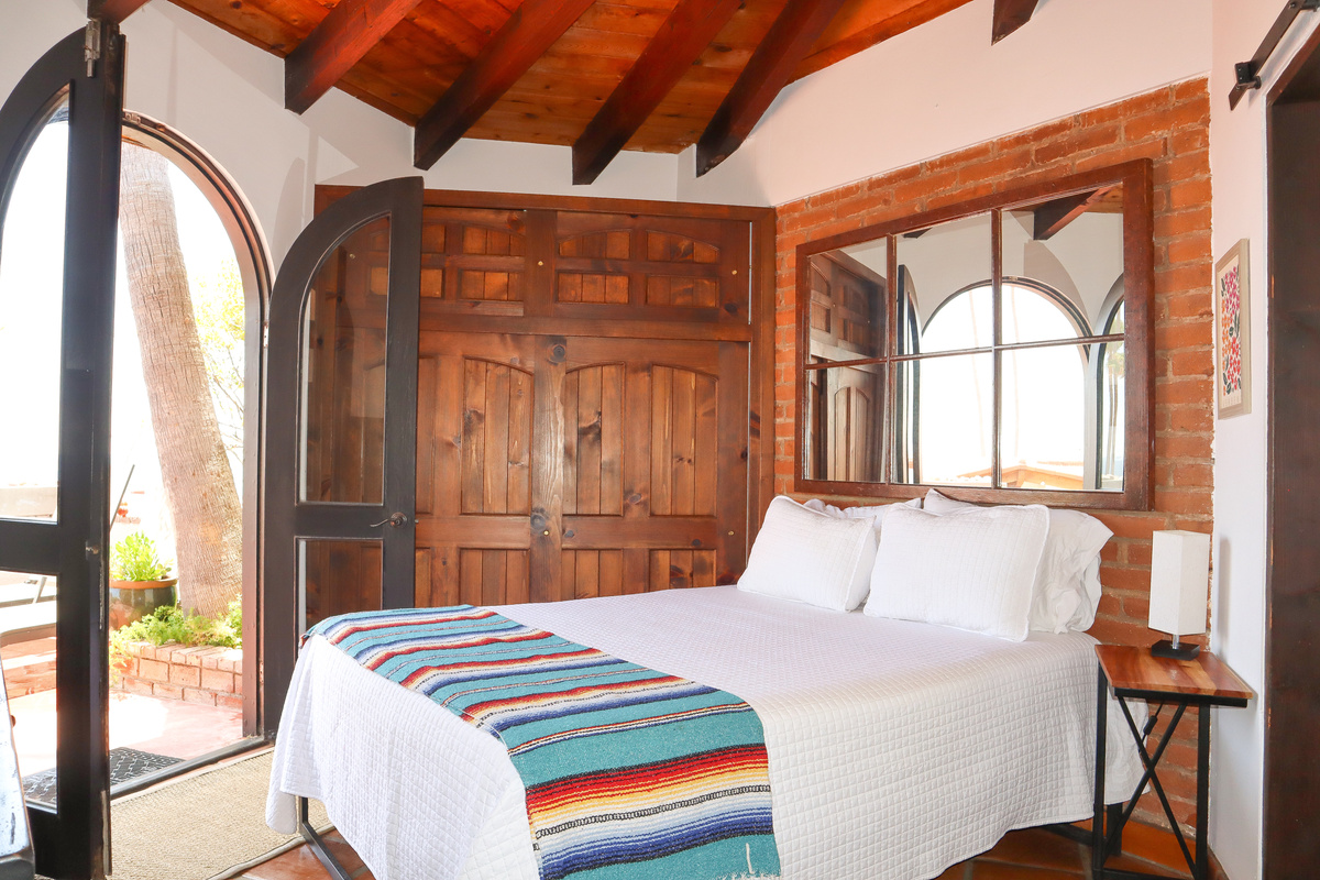 Queen-size bed, Luxury linens, Ceiling fan, French doors opening to patio, Adjacent bathroom with shower.