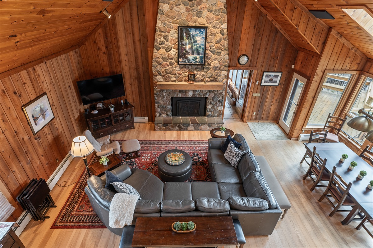 Open-beam great room with leather seating and stone fireplace — perfect for cozy nights or family movie time.