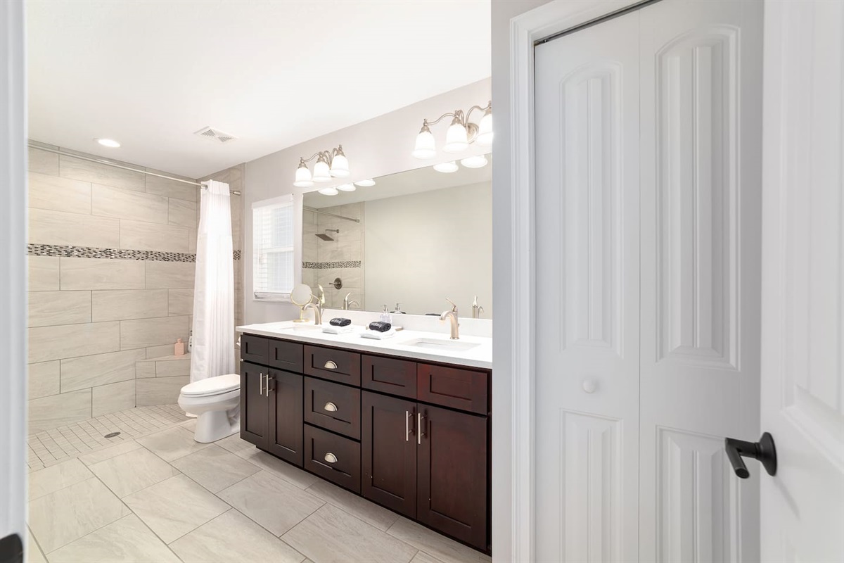 Enjoy a beautiful  en-suite featuring a large walk-in shower, a double-sink vanity with plenty of counter space, bright lighting, and thoughtful touches throughout. This fresh, spa-like bathroom offers comfort and convenience for a relaxing stay.