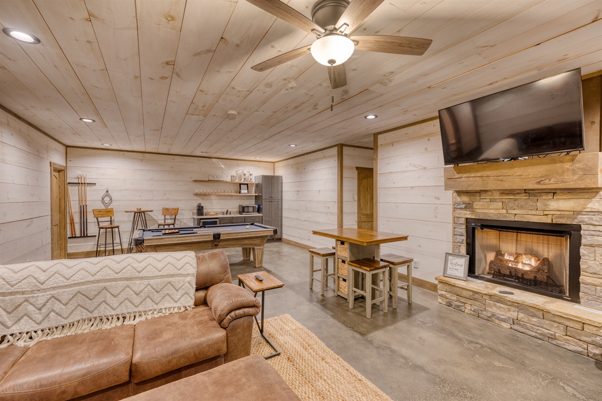 Basement living area with seating for watching tv, game table, pool table and wet bar