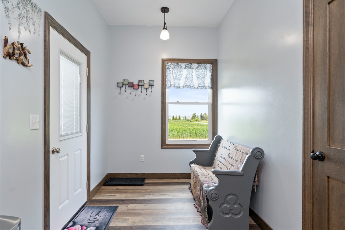 Welcoming back entryway with charming farmhouse bench and bright natural light, for easy access to the back of the property.