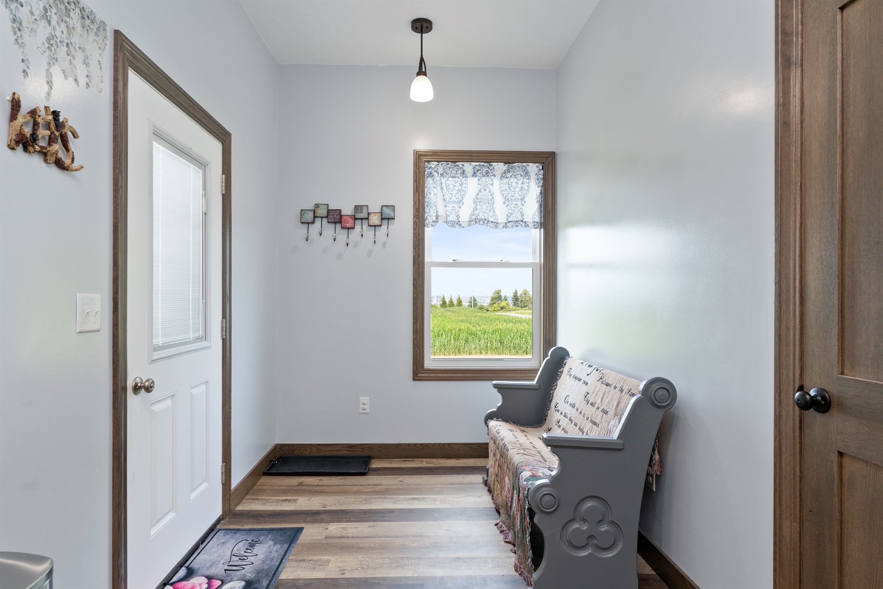 Welcoming back entryway with charming farmhouse bench and bright natural light, for easy access to the back of the property.